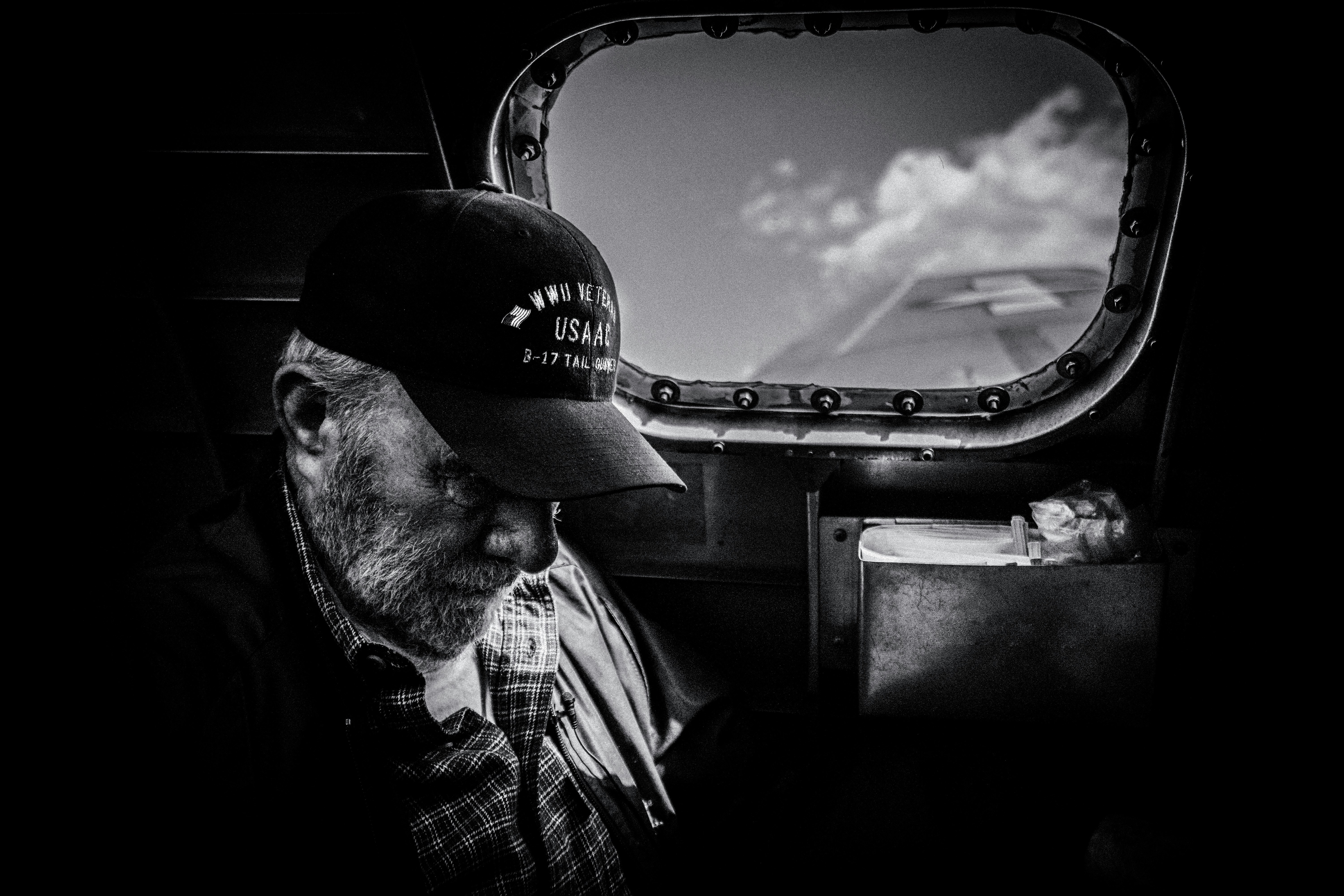 grayscale photo of man in plaid shirt and cap looking at the sky
